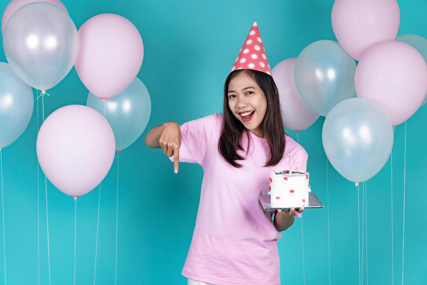 Portrait of Cheerful Young Asian Woman Celebrating Birthday And Pointing Down photo