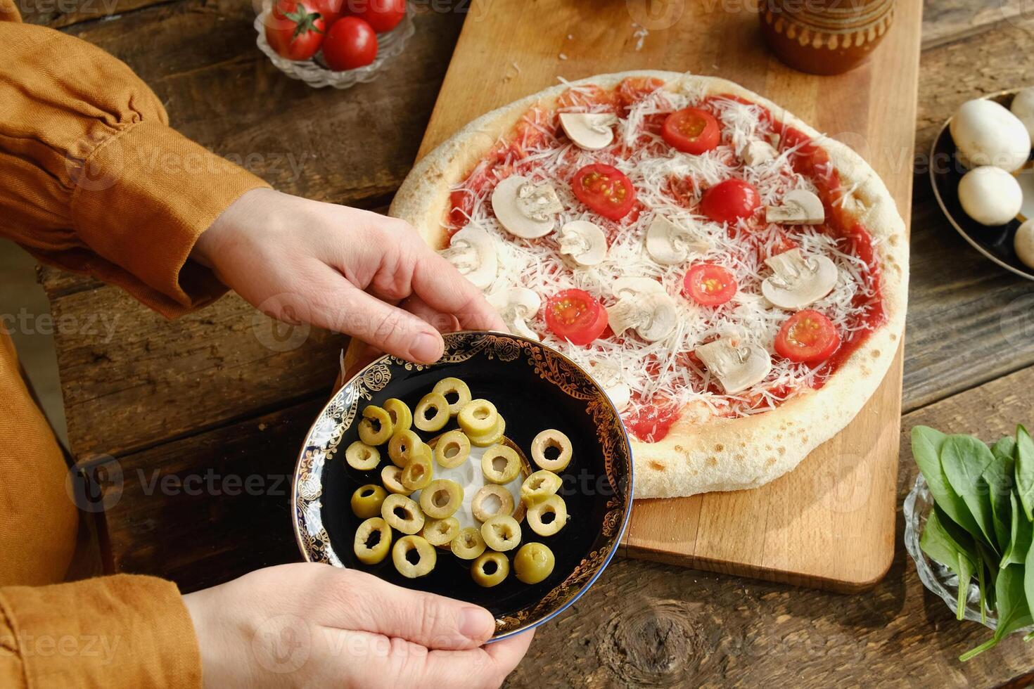 Making pizza. Woman cooking homemade pizza and putting olives on dough photo