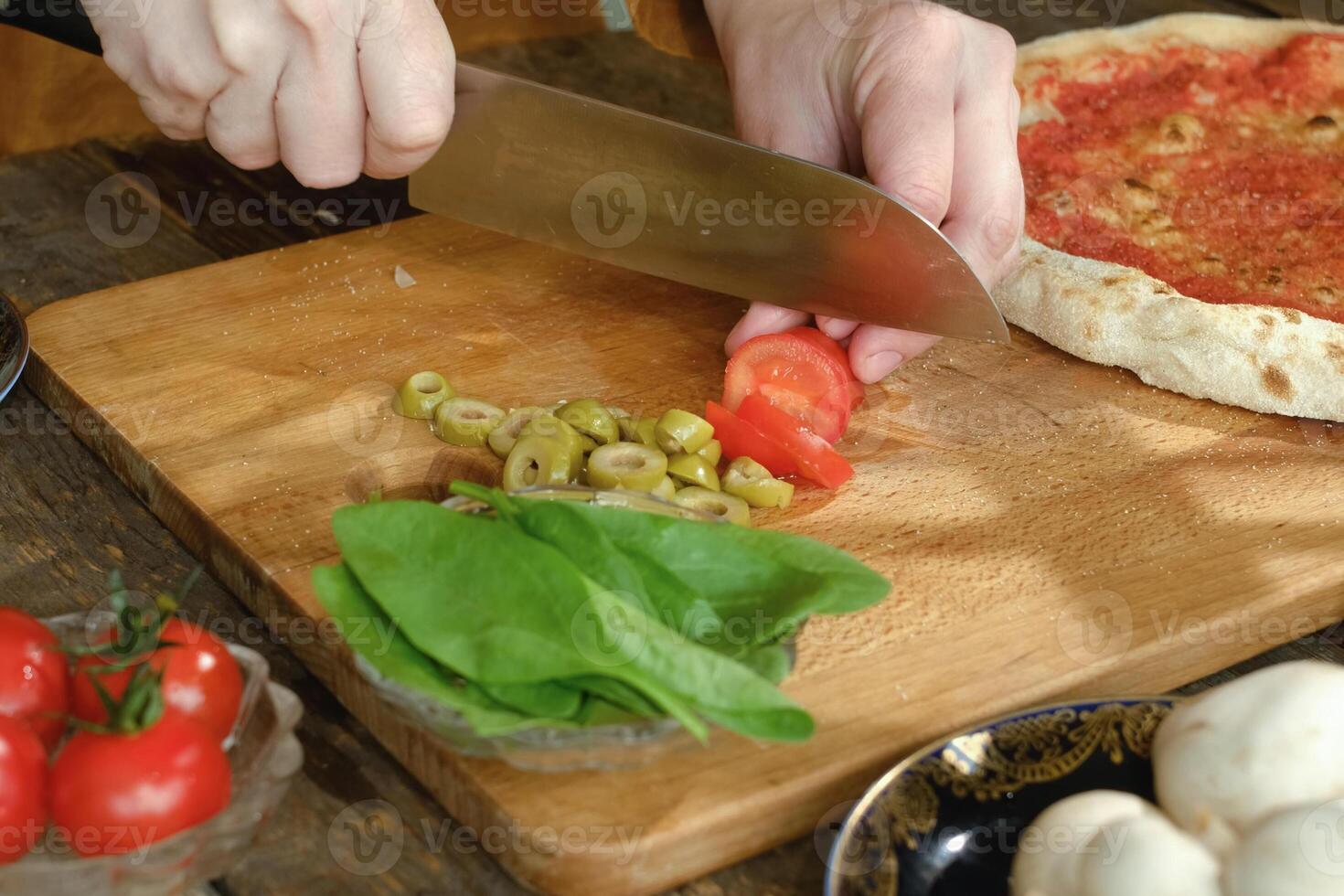 Making homemade pizza. Hands cutting ingredients for pizza photo