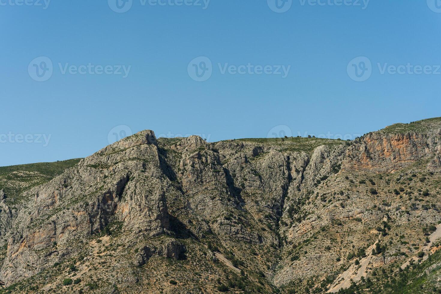 A plane flying over a mountain with a blue sky photo