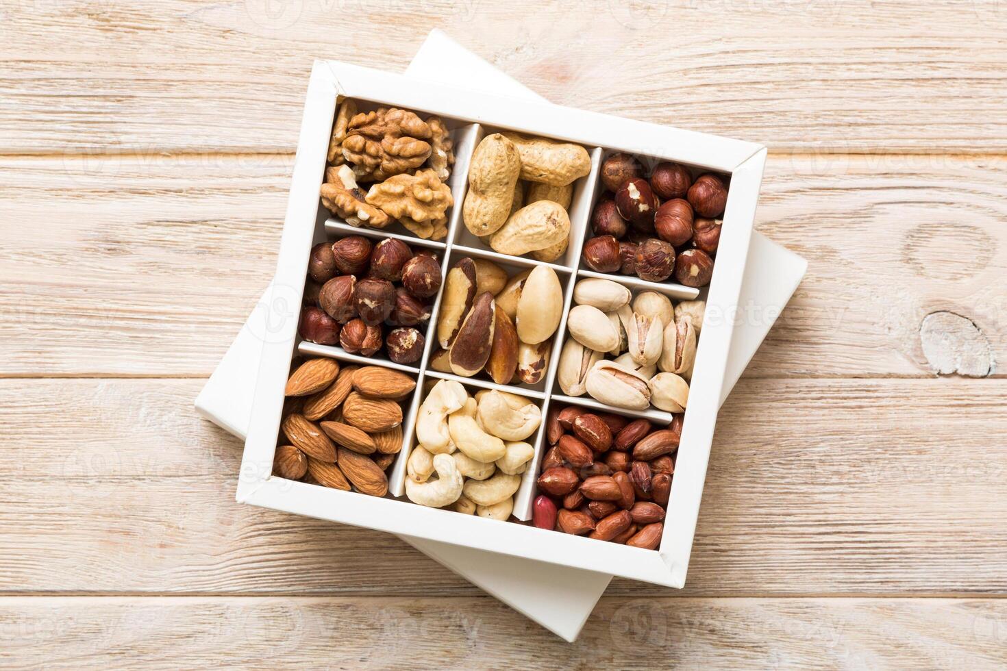 Various varieties of nuts lying in paper box on table background. Top view. Healthy food. Close up, copy space, top view, flat lay. Walnut, pistachios, almonds, hazelnuts photo