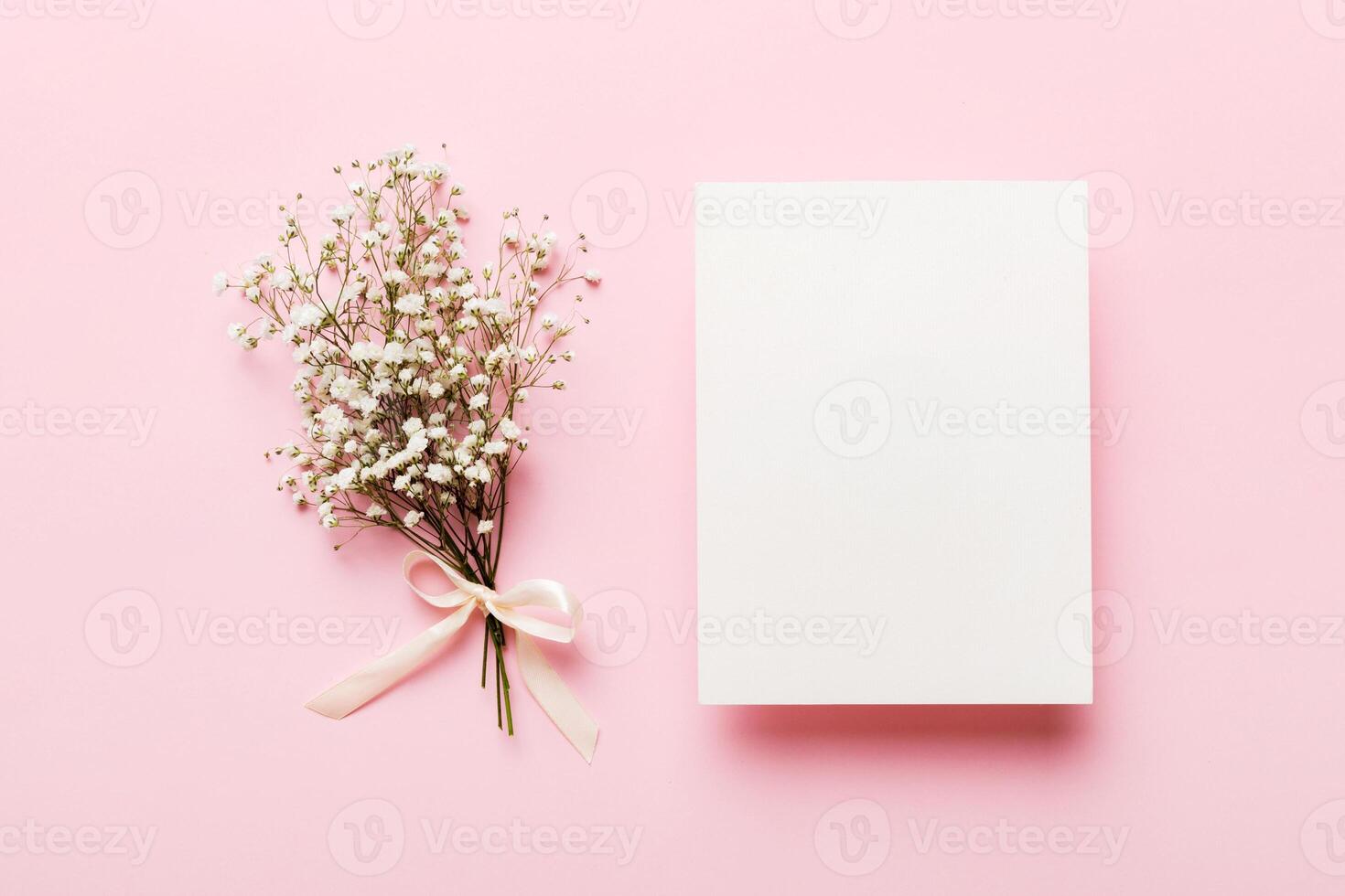 Wedding mockup with white paper list and flowers gypsophila on colored table top view flat lay. Blank greeting cards and envelopes photo