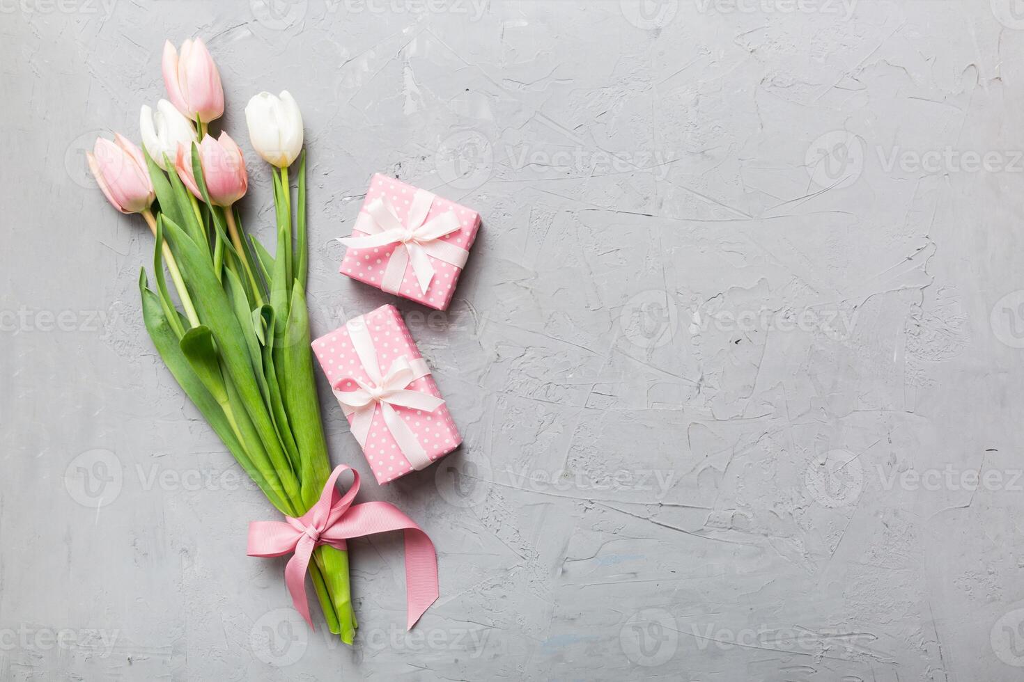 Pink tulips flowers and gift present box on colored table background. Mothers Day, Womens Day, celebration concept. Space for text photo