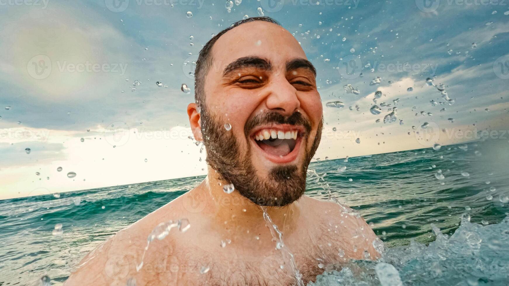 Happy man swing in a sea and water drops hitting him photo
