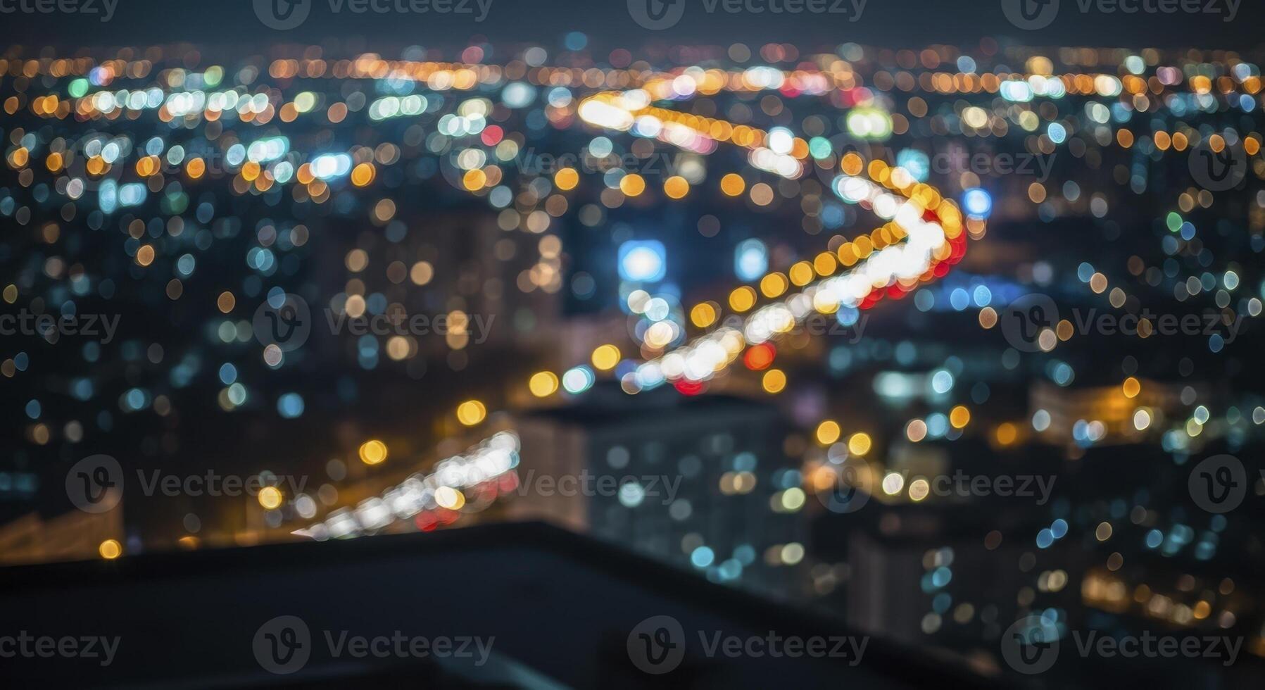Defocused city nightscape with vibrant bokeh lights and blurry traffic trails on a winding road photo