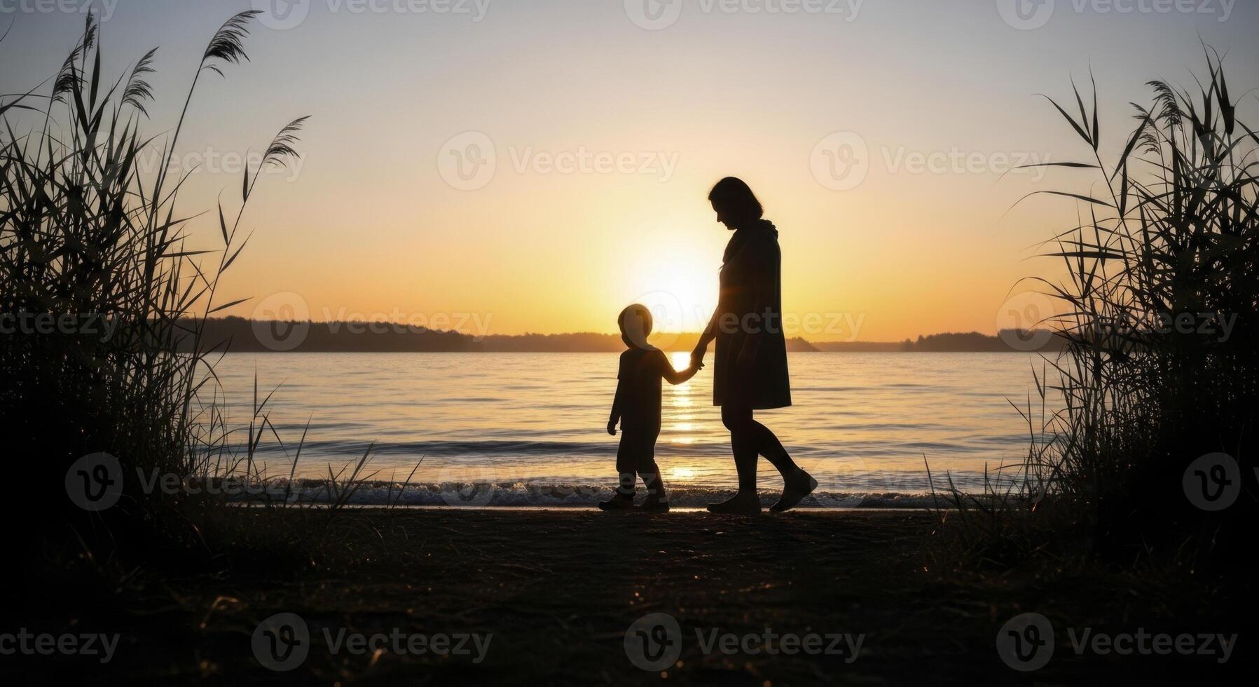 Silhouette of mother and son walking hand in hand at lakeside sunset photo