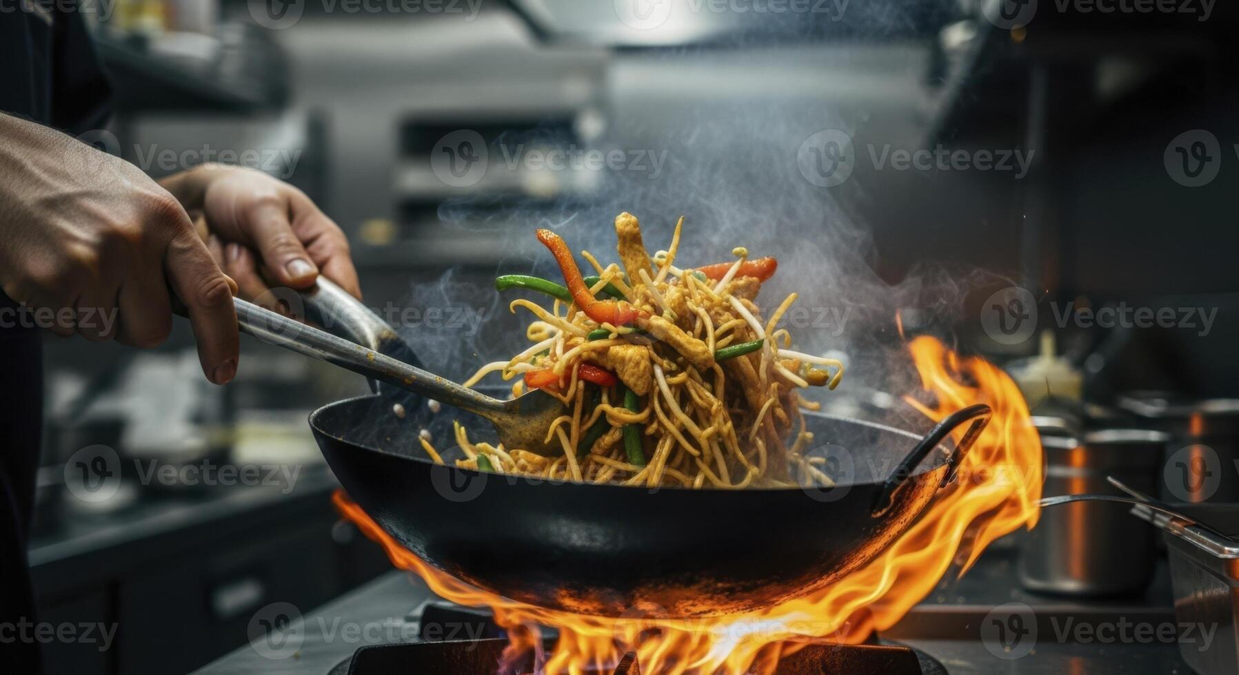 Professional chef rapidly tossing stir fried noodles in a sizzling wok with high flames photo