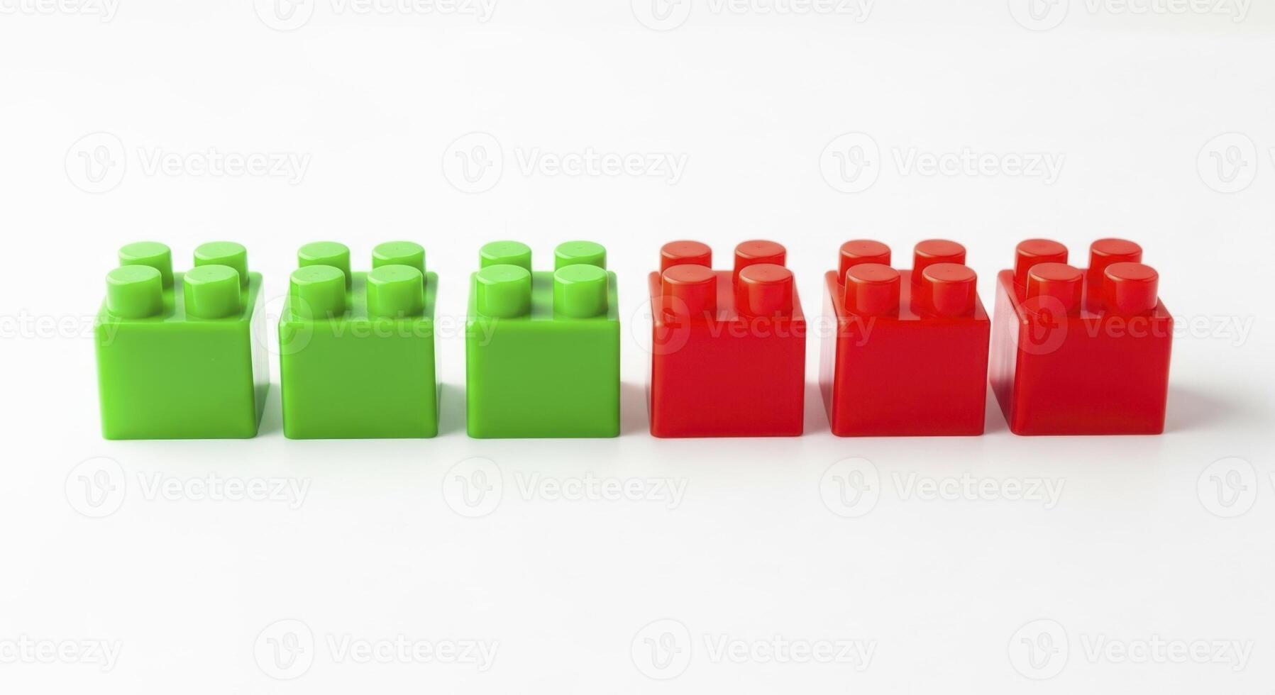 Bright green and red plastic construction blocks neatly aligned on a simple white studio surface. photo