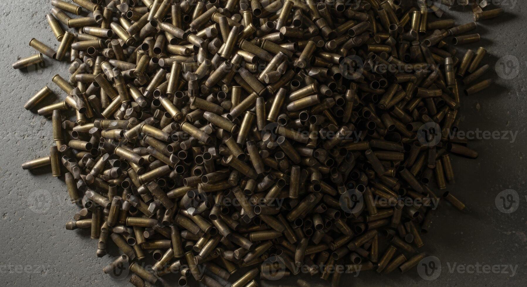 Chaotic pile of spent brass shell casings, some tarnished and gleaming, on a dark surface photo