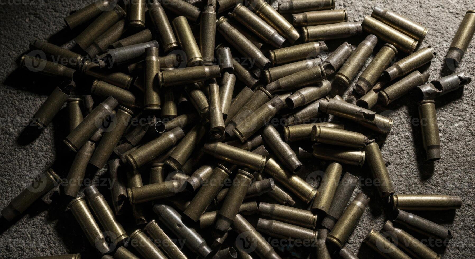 Large pile of spent brass shell casings on a dark textured surface photo