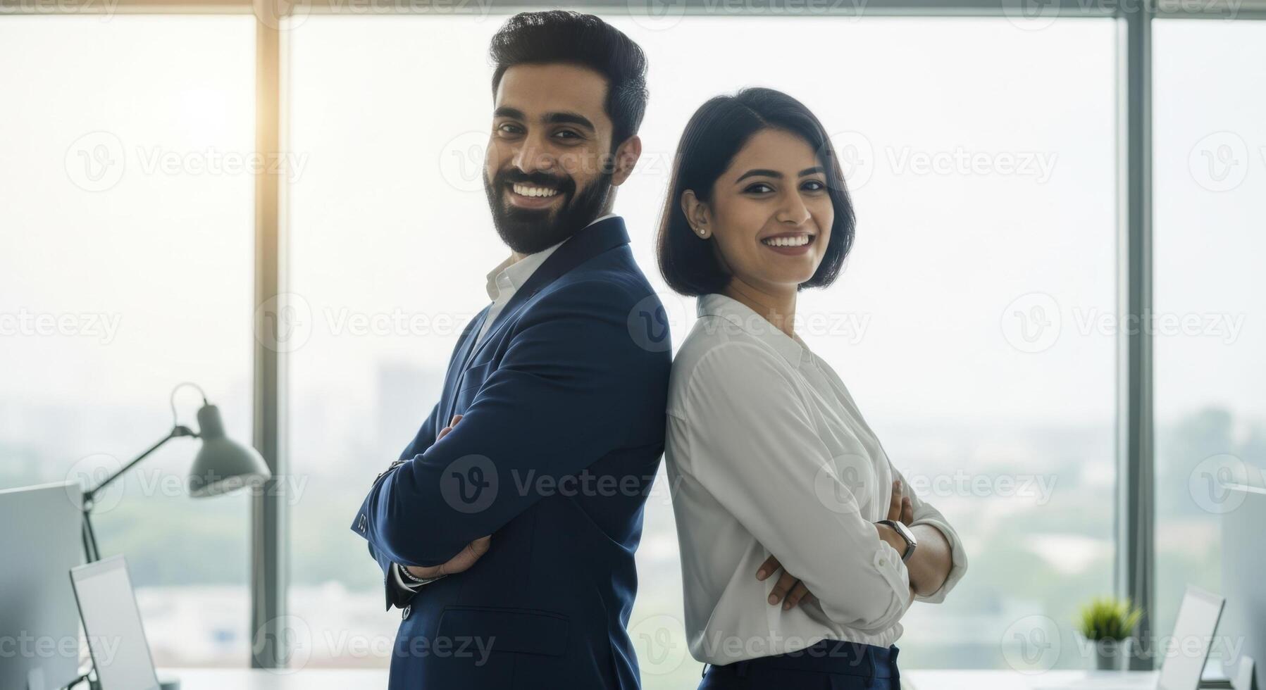 Young indian business professionals standing back to back in modern office smiling photo