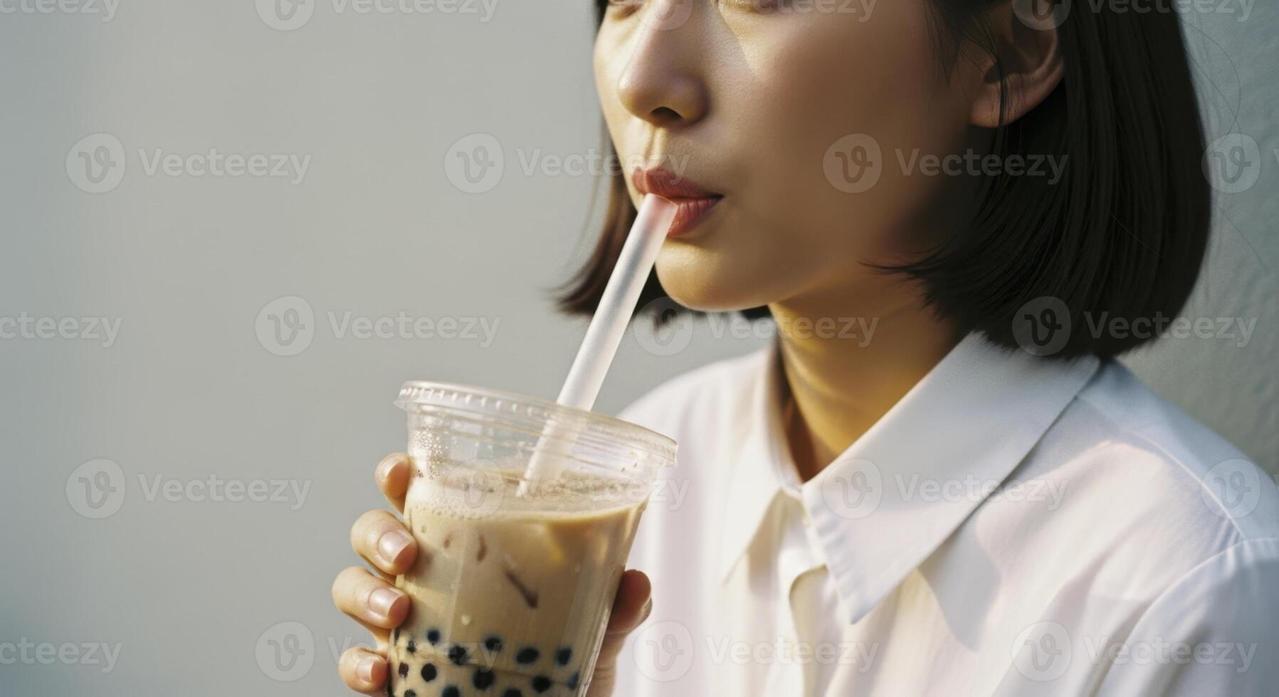 Young asian woman enjoying refreshing iced bubble tea with a straw outdoors photo