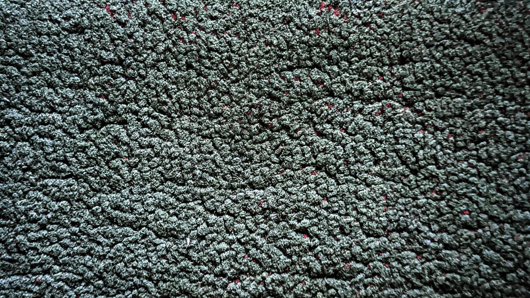 A close up of a carpet with green and red spots photo