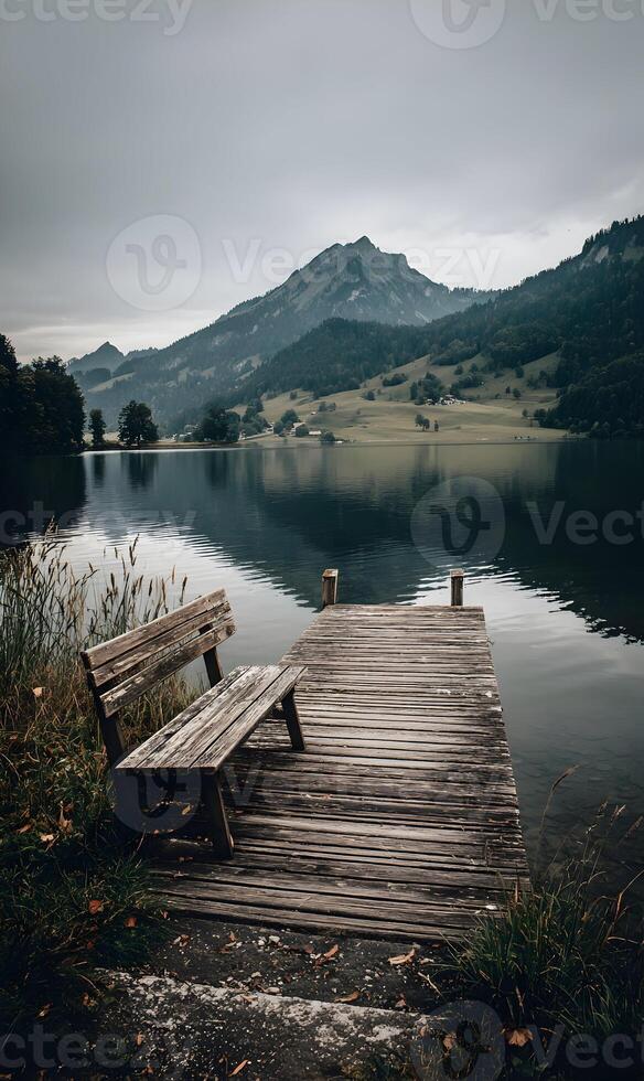 Wooden Pier with a Bench Overlooking Serene Lake Reflections of Mountains Under Cloudy Sky Ambience photo