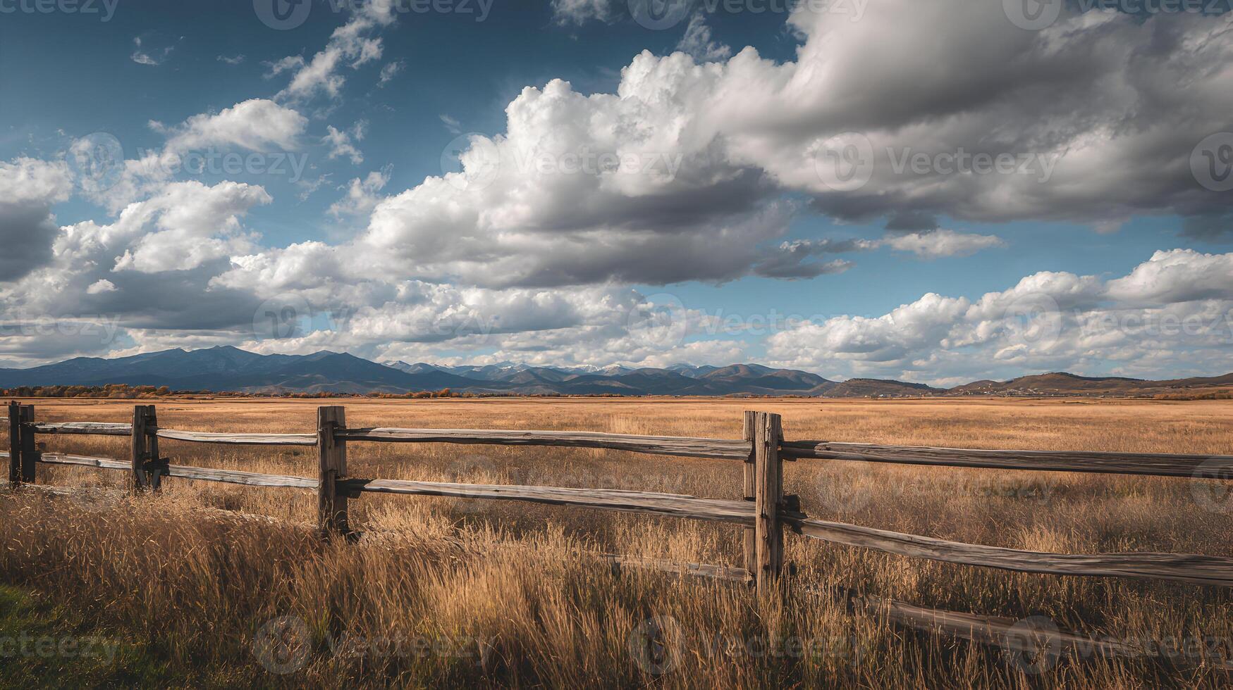 Idyllic prairie landscape with wooden fence and mountain scenery backdrop under cloudy sky photo