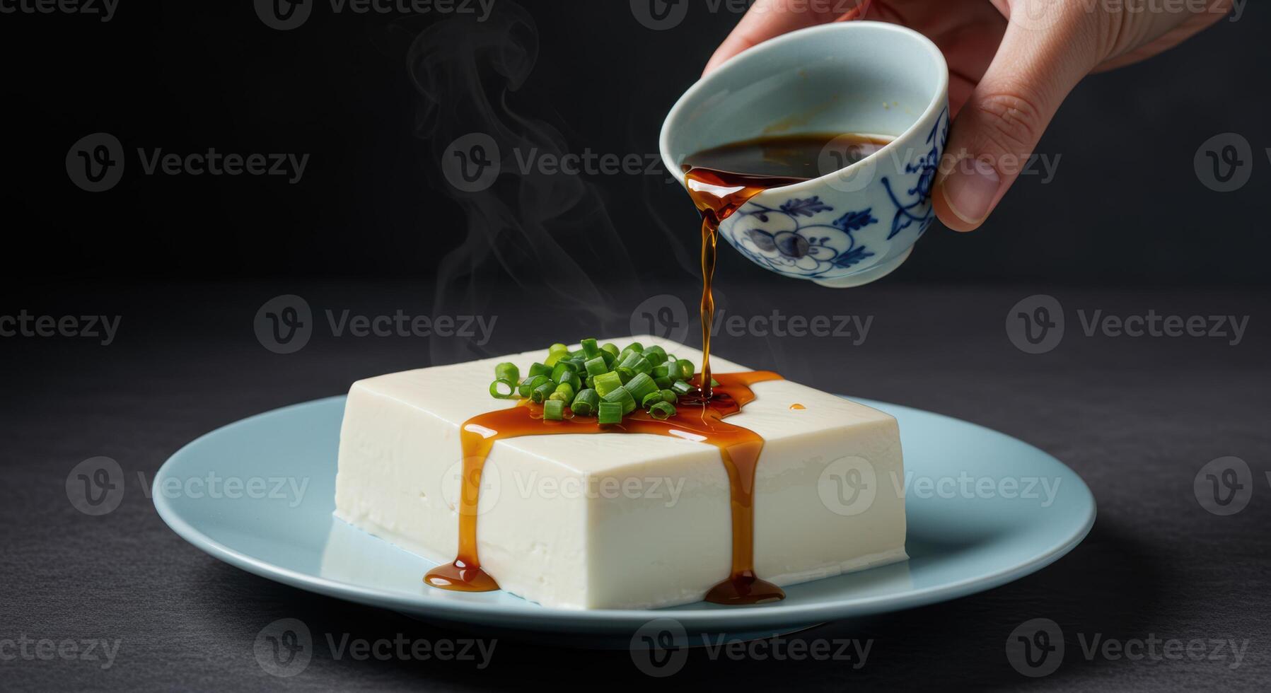 Fresh white tofu with green onions and savory sauce served on a light blue plate photo