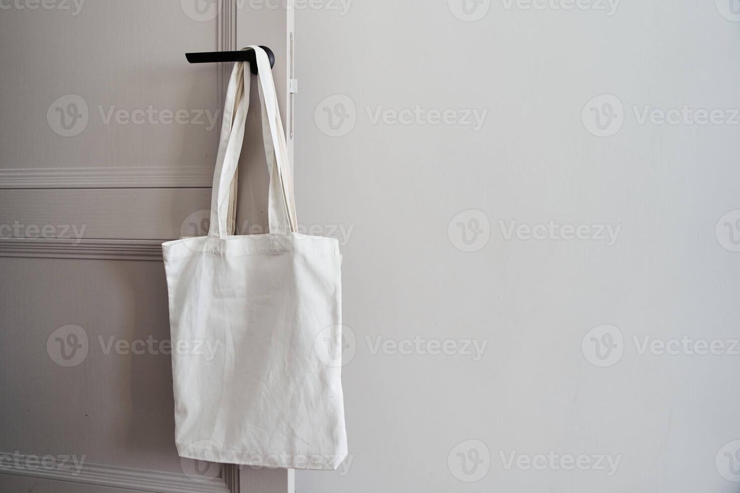 White eco friendly bag hanging on the door handle. Canvas tote bag photo