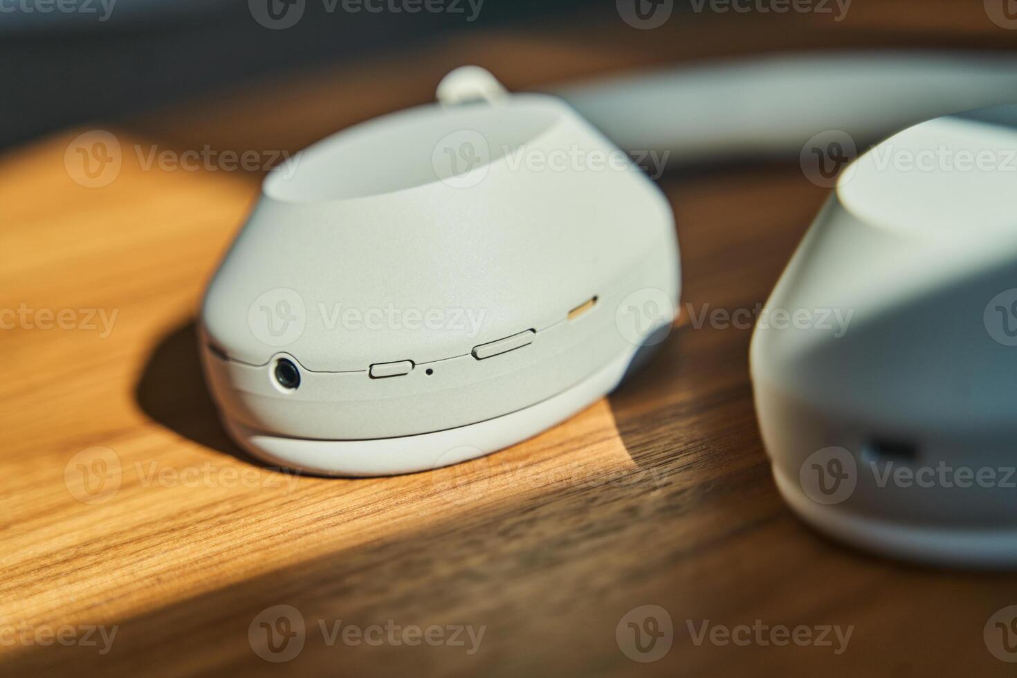 Large white wireless headphones lying on a wooden table photo