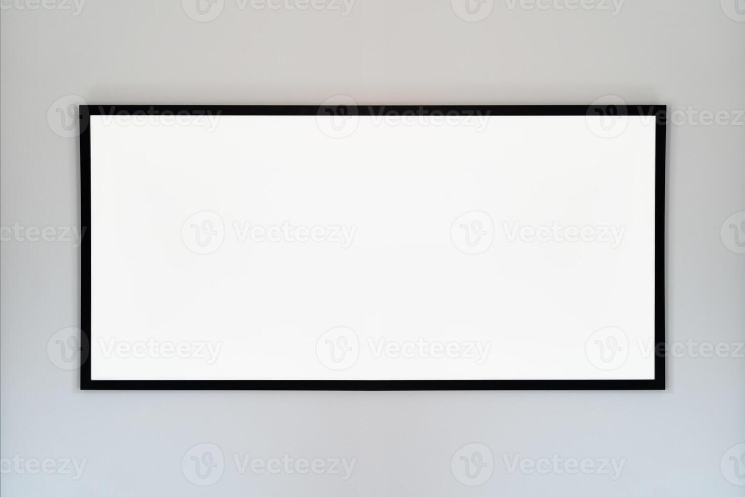 An empty photo frame with a black border hanging on a white wall