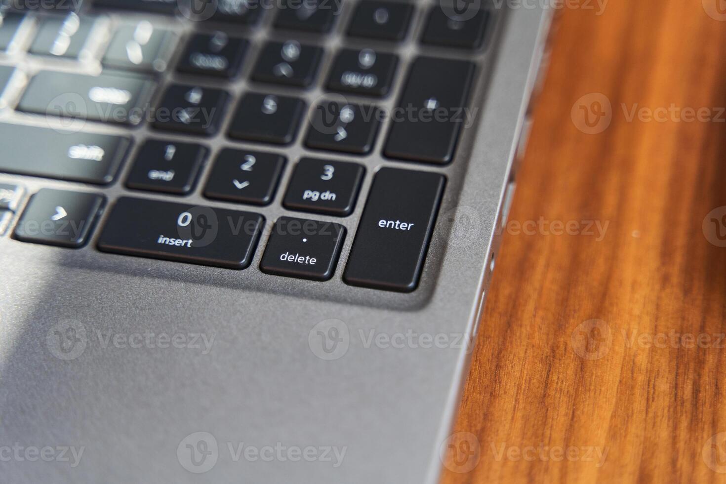 Top view of a part of a gray laptop keyboard on a wooden table photo