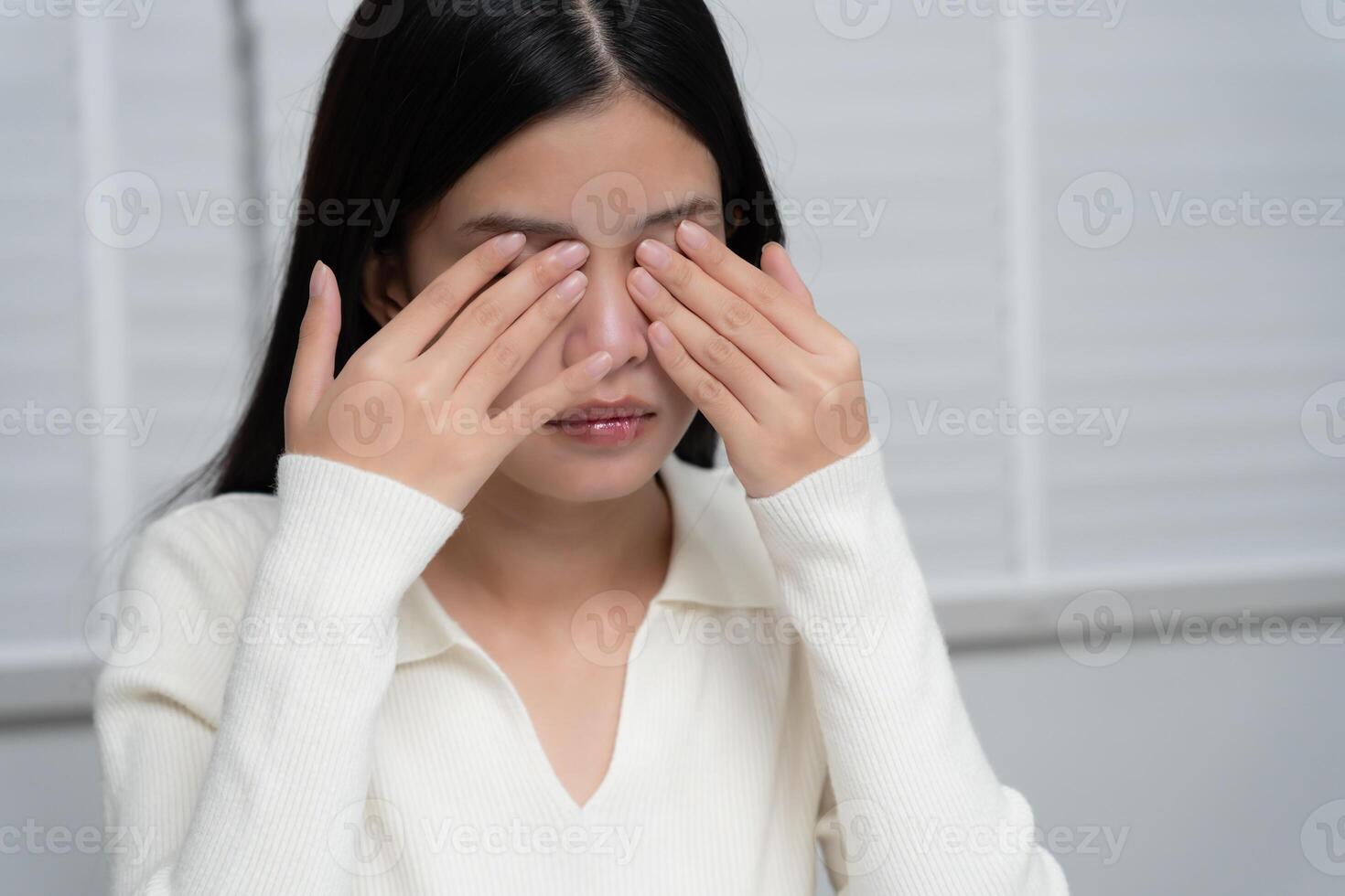 Asian women with tired and irritated eyes, eye rubbing, dry, eye pain after work, migraine, headache, blurred vision, photophobia, working in the dark, blue light from computer screens photo