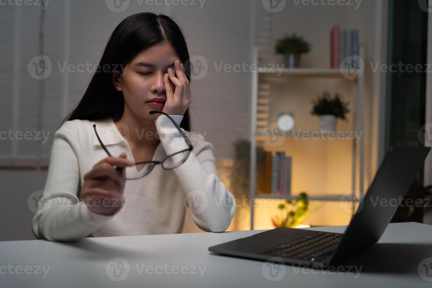 Eye problem. Asian women with tired and irritated eyes, eye rubbing, dry, eye pain after work, migraine, headache, blurred vision, photophobia, working in the dark, blue light from computer screens photo
