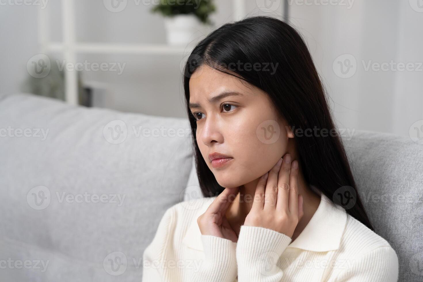 Asian woman put on neck due to a sore throat. female tonsillitis causes a inflammation. treated by taking water, taking antibiotics, consult a doctor virus, corona virus, Influenza. photo