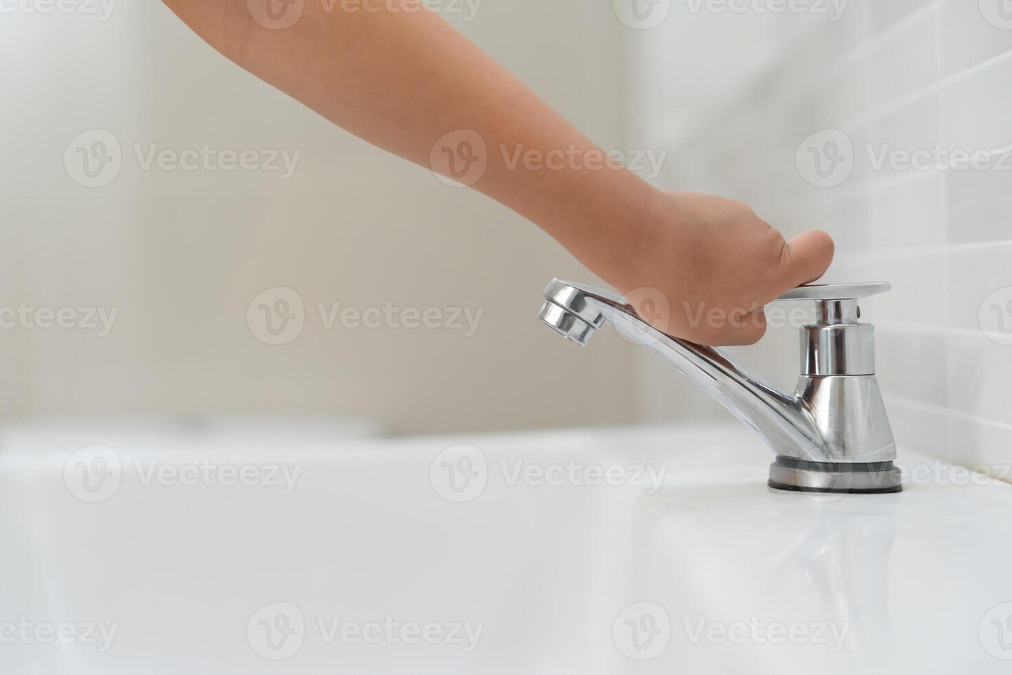 Little kid hand closed the faucet at sink in house with mom. Mother teaches child to save water. keeps turning off the water to save world energy and protect the environment. photo