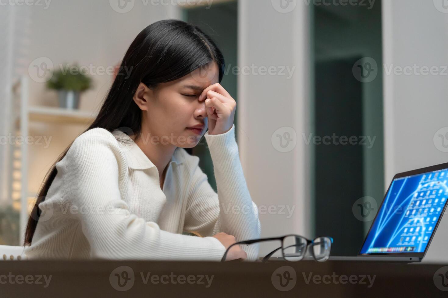 Eye problems. Asian women with tired and irritated eyes, eye rubbing, dry, eye pain after work, migraine, headache, blurred vision, photophobia, working in the dark. blue light from computer screens photo