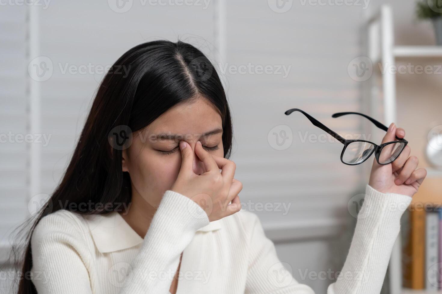 Eye problems Asian women with tired and irritated eyes, eye rubbing, dry, eye pain after work, migraine, headache, blurred vision, photophobia, working in the dark, blue light from computer screens photo