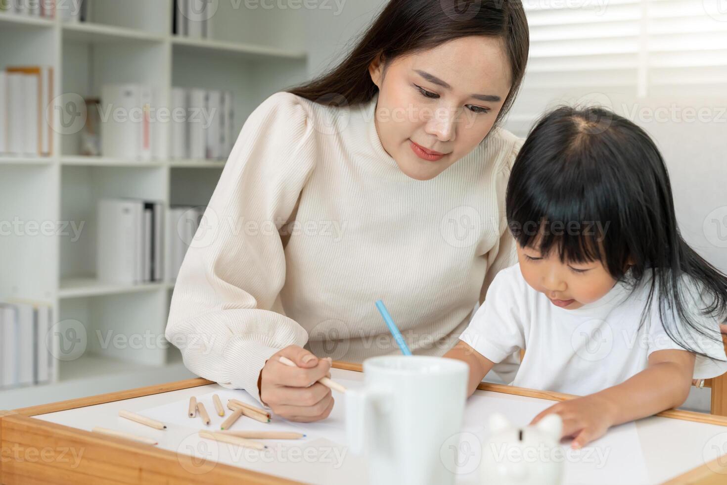 Happy Asian mother playing learning paint for little girl. Funny family is happy and excited in the house. Mother and daughter having fun spending time together. Holiday. photo