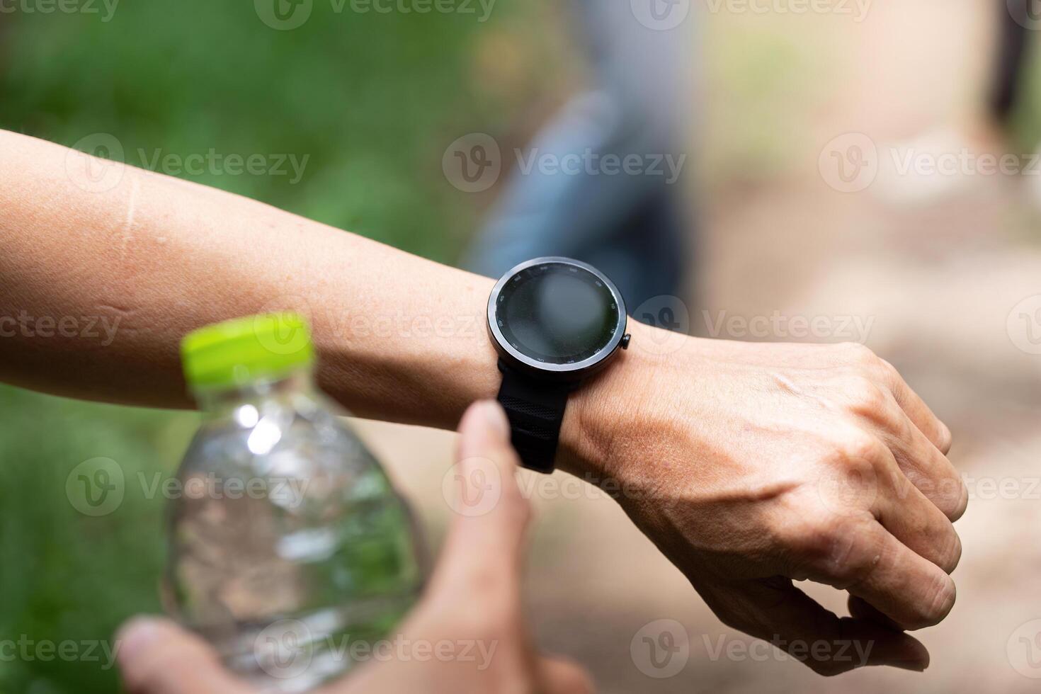 Close-Up of Smartwatch and Water Bottle. A detailed view of a smartwatch and water bottle during a hiking trip. photo