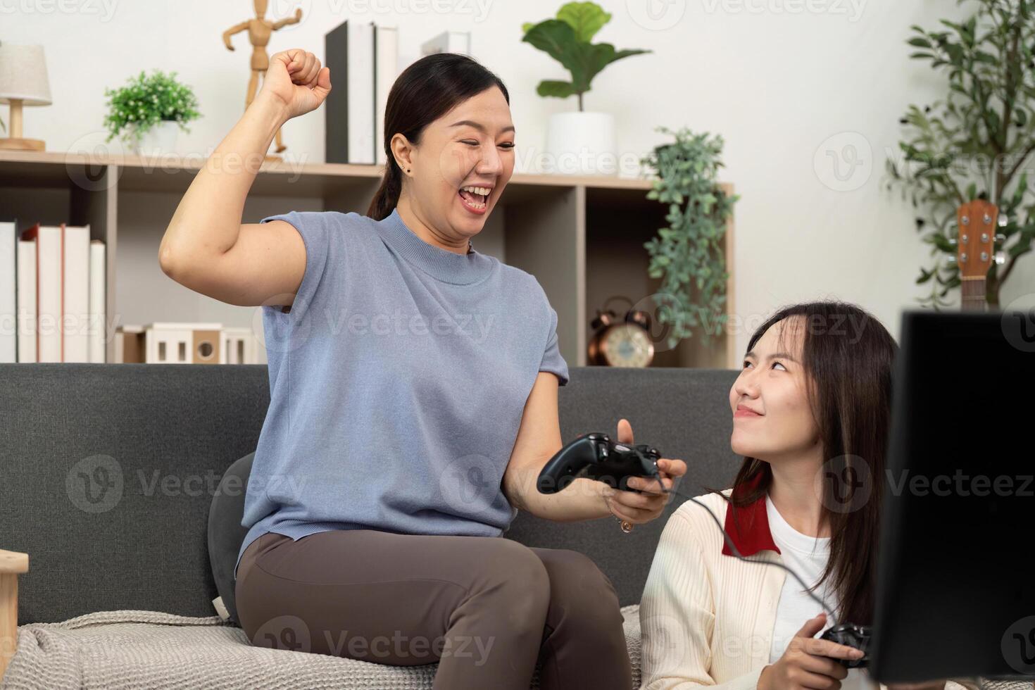 Excited Mother Celebrating a Win While Gaming with Daughter photo