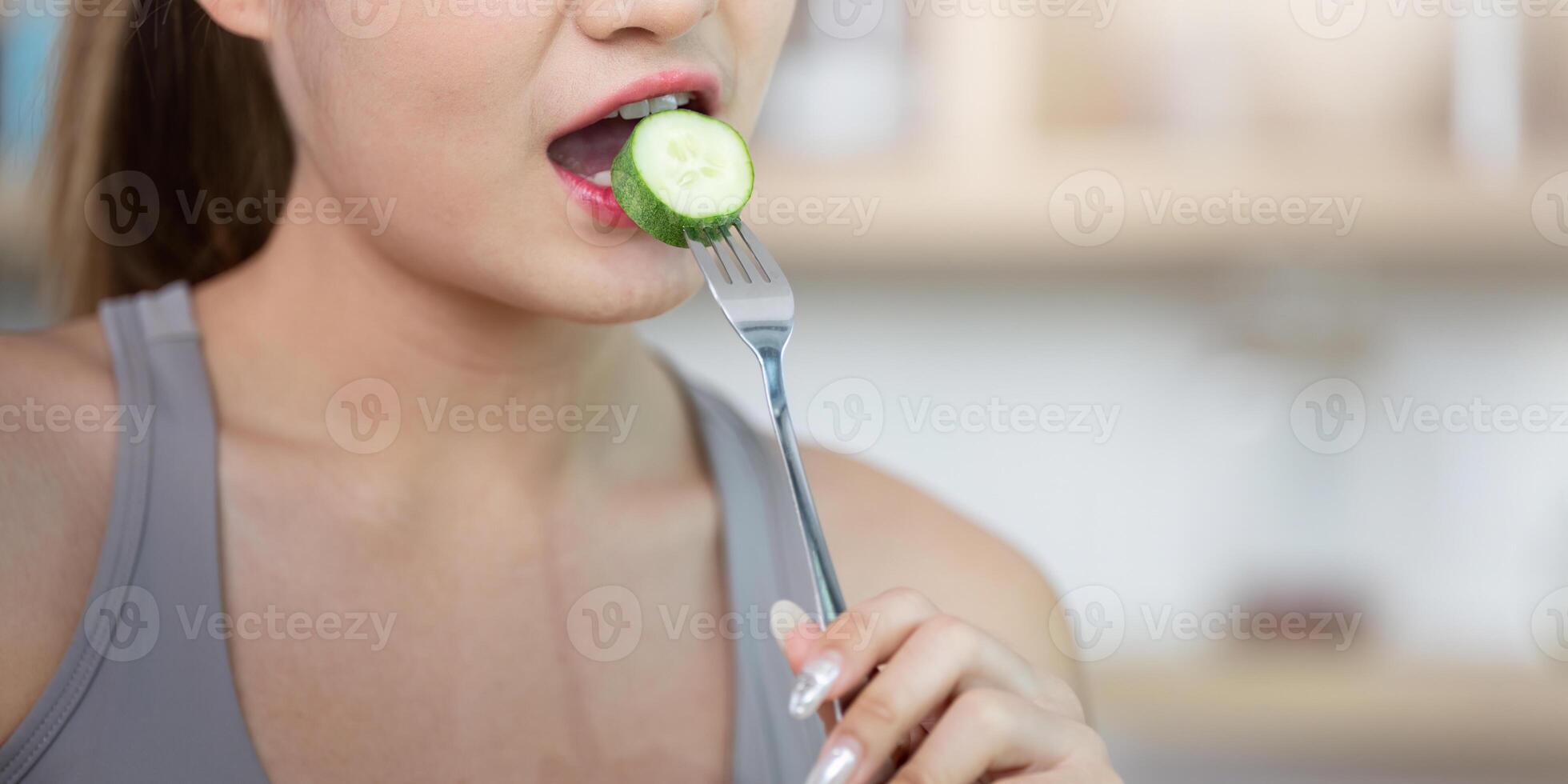 Wellness and Healthy Eating. Woman enjoying cucumber slice for nutritious diet. photo