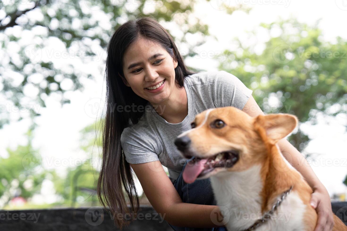 Joyful Bonding with Pet. Young woman playing with her corgi dog in a sunny park. photo