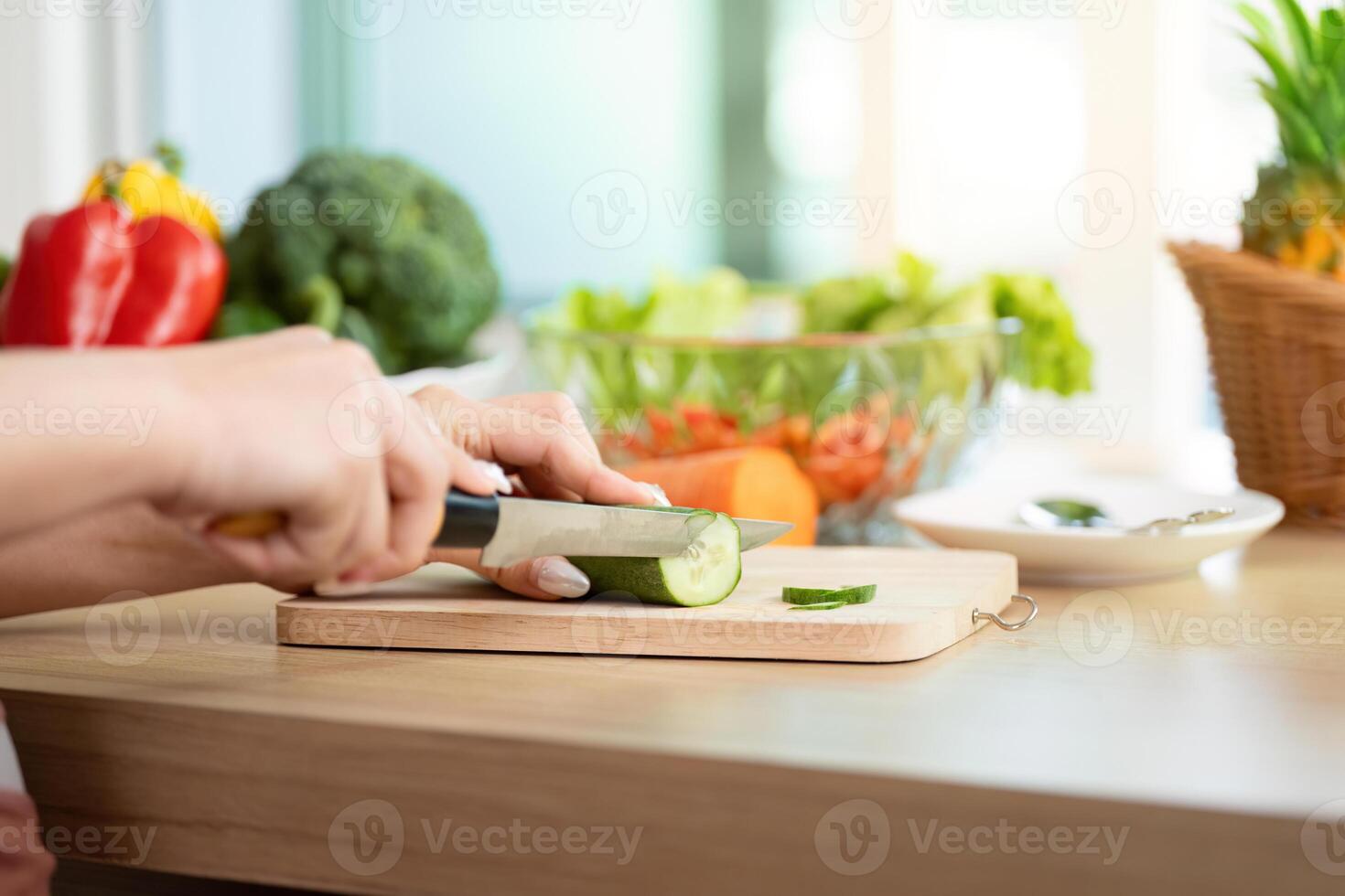 Wellness and Meal Preparation. Close-up of a woman slicing cucumber for a healthy dish. photo