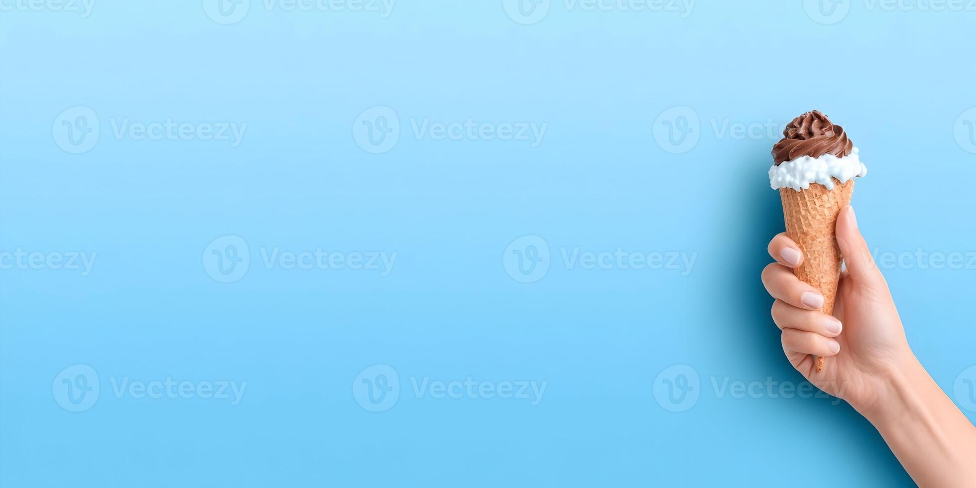 Hand Holding Chocolate Ice Cream Cone with Whipped Cream on Blue Background photo