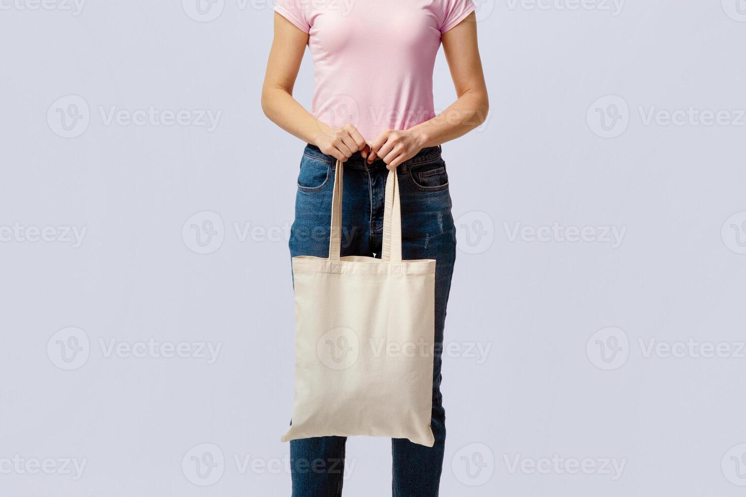 No More Plastic. Cropped Image Of Woman Holding Blank White Canvas Eco Tote Bag With Free Copy Space For Your Logo Or Design, Unrecognizable Lady Standing Over Light Grey Studio Background photo