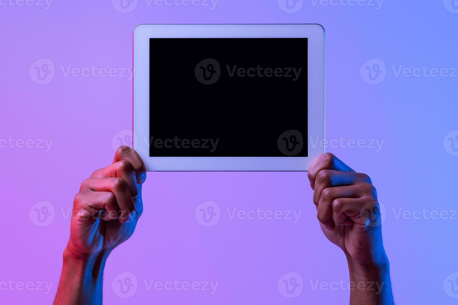 Hands Of African American Man Holding Digital Tablet With Black Blank Screen, Showing Free Copy Space For Your App Or Website Design, Standing In Neon Lighting Over Purple Studio Background, Mockup photo