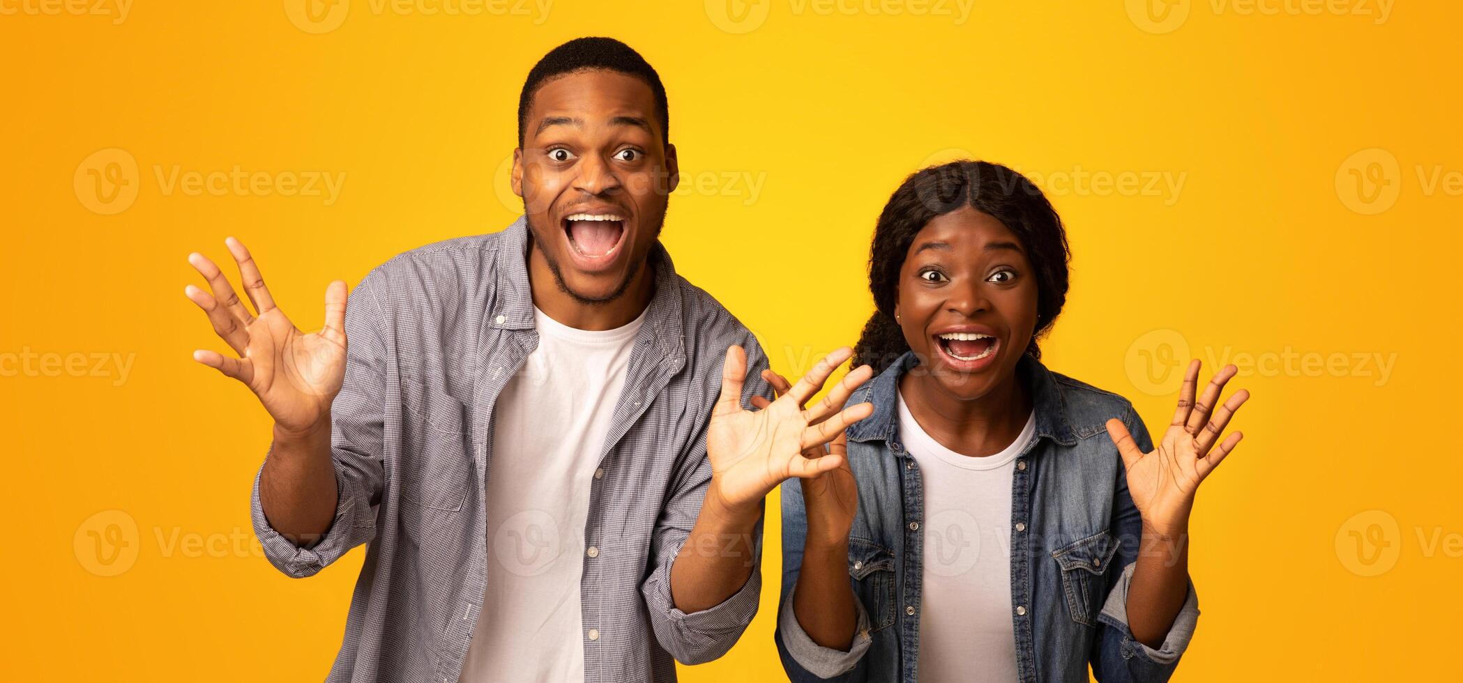 Surprised Black Couple Exclaiming With Excitement And Spreading Hands Over Yellow Studio Background And Looking At Camera, Overjoyed Emotional African Man And Woman Celebrating Success, Free Space photo