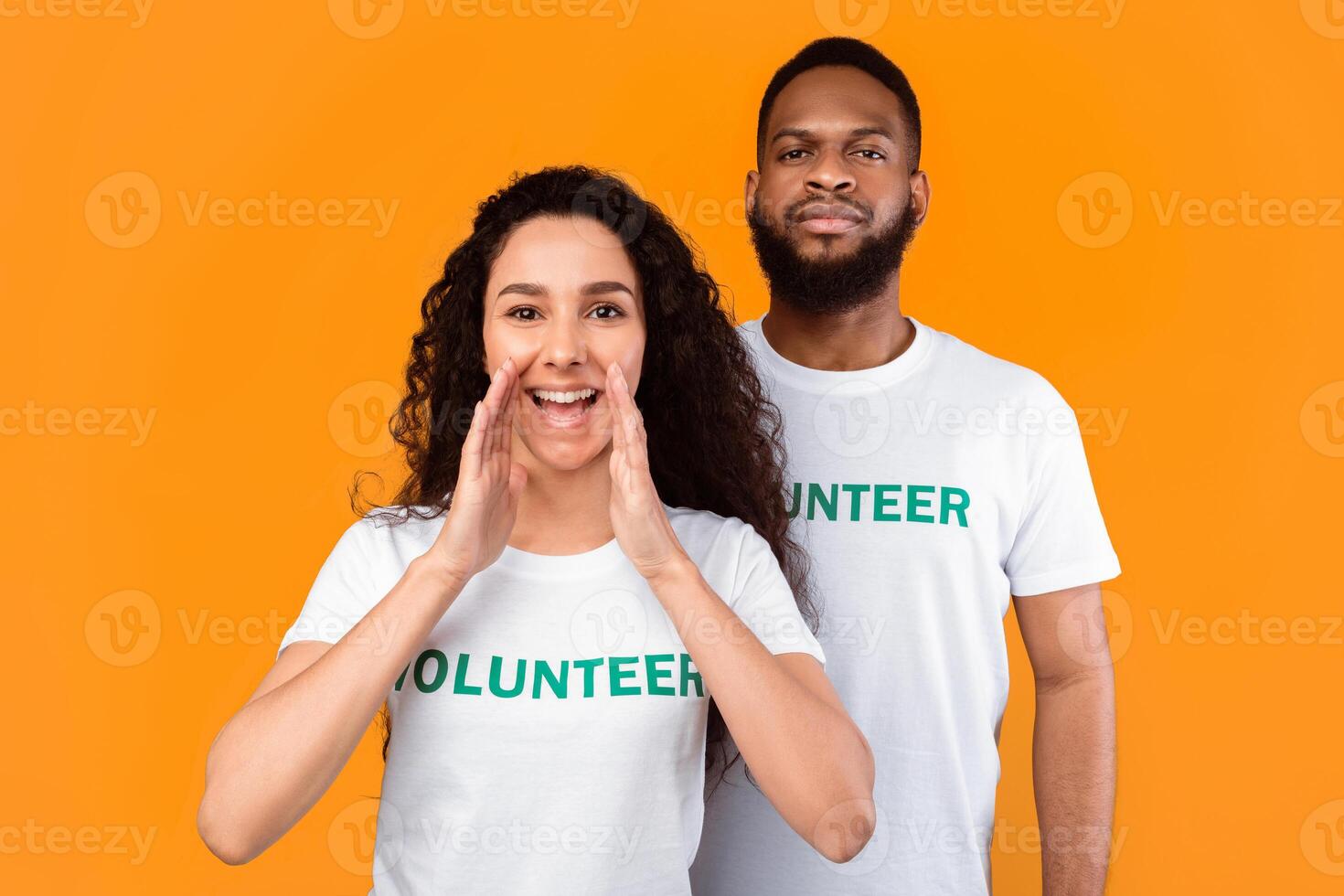 Hey, Volunteering Advertisement. Two Cheerful Diverse Volunteers Shouting Holding Hands Near Mouth, Calling You And Drawing Your Attention Standing Over Yellow Studio Background photo