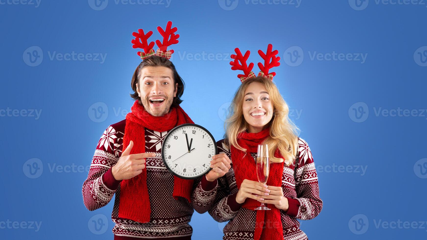 New Year celebration. Affectionate young couple with champagne and clock showing five minutes till midnight, blue background photo