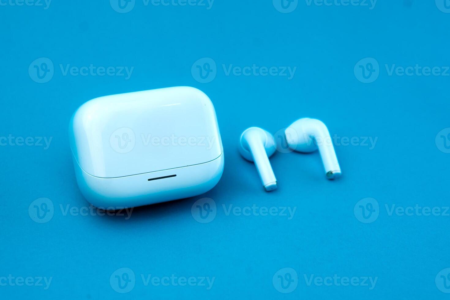 Stylish pair of wireless earbuds with a closed charging case on a blue background. The compact and modern design makes it ideal for music, calls, and on-the-go listening. photo