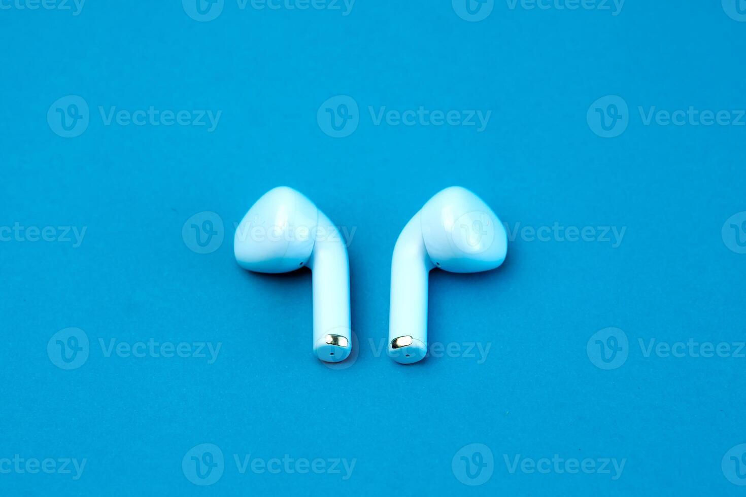 Pair of modern wireless earbuds on a vibrant blue background. Stylish and compact Bluetooth earphones designed for high-quality audio, seamless connectivity, and everyday convenience. photo