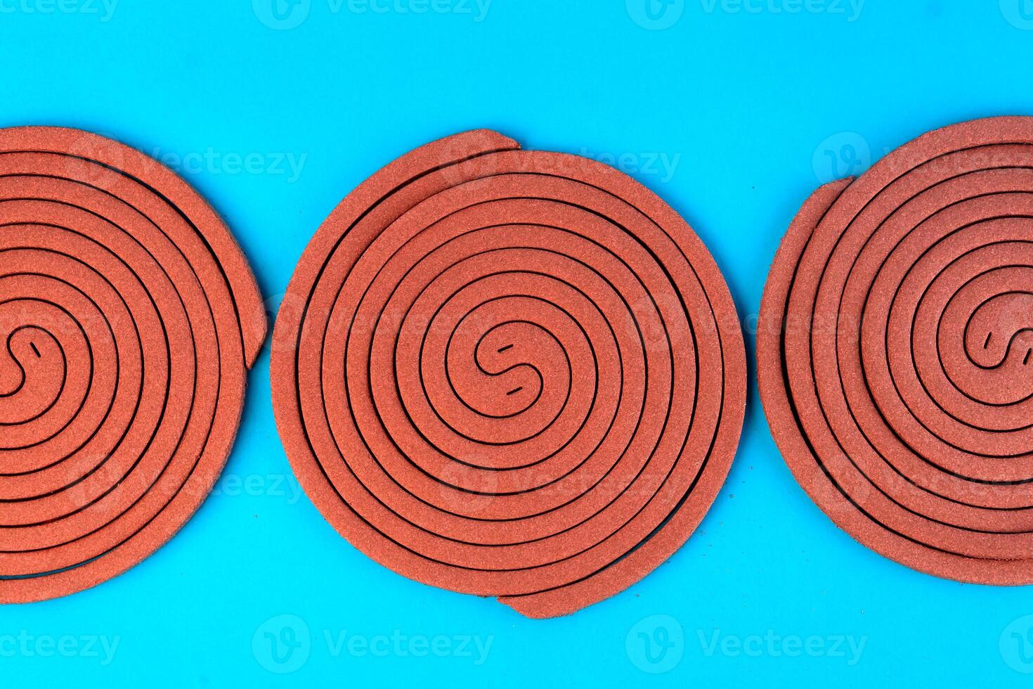 Three brown mosquito coils in a spiral shape on a blue background. Insect repellent for indoor and outdoor use, designed to keep mosquitoes away and provide protection from bites. photo
