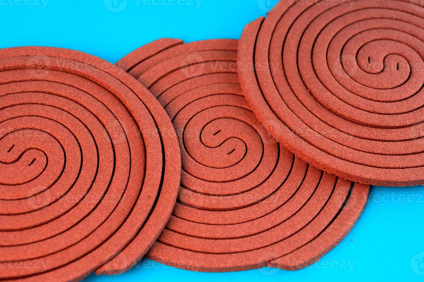 Multiple brown mosquito coils in a spiral pattern on a blue background. Traditional insect repellent designed to keep mosquitoes away for indoor and outdoor protection. photo