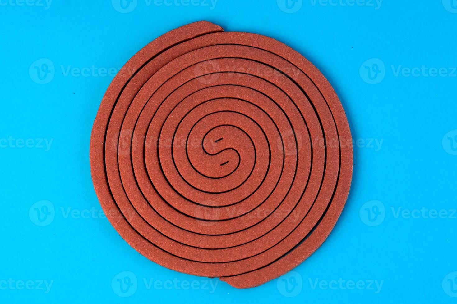 A brown mosquito coil in a spiral shape on a blue background. Insect repellent for outdoor and indoor use, designed to keep mosquitoes away and provide protection from bites. photo