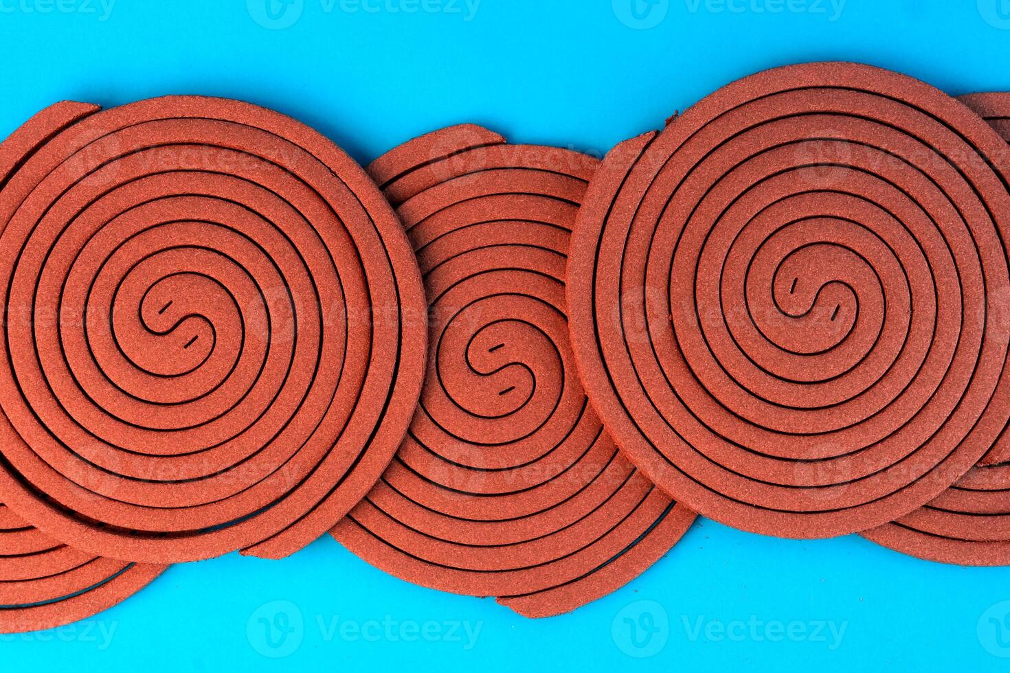 A Multiple brown mosquito coils in a spiral pattern on a blue background. Traditional insect repellent designed to keep mosquitoes away for indoor and outdoor protection. photo