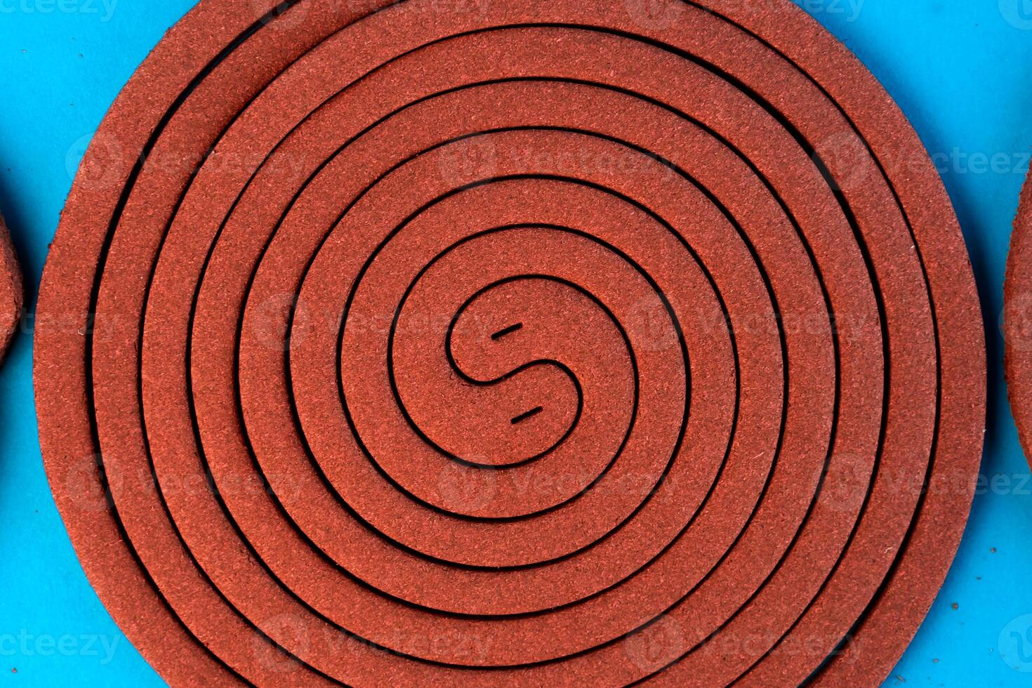 A mosquito coil in a spiral shape on a blue background. Insect repellent for outdoor and indoor use, designed to keep mosquitoes away and provide protection from bites. photo