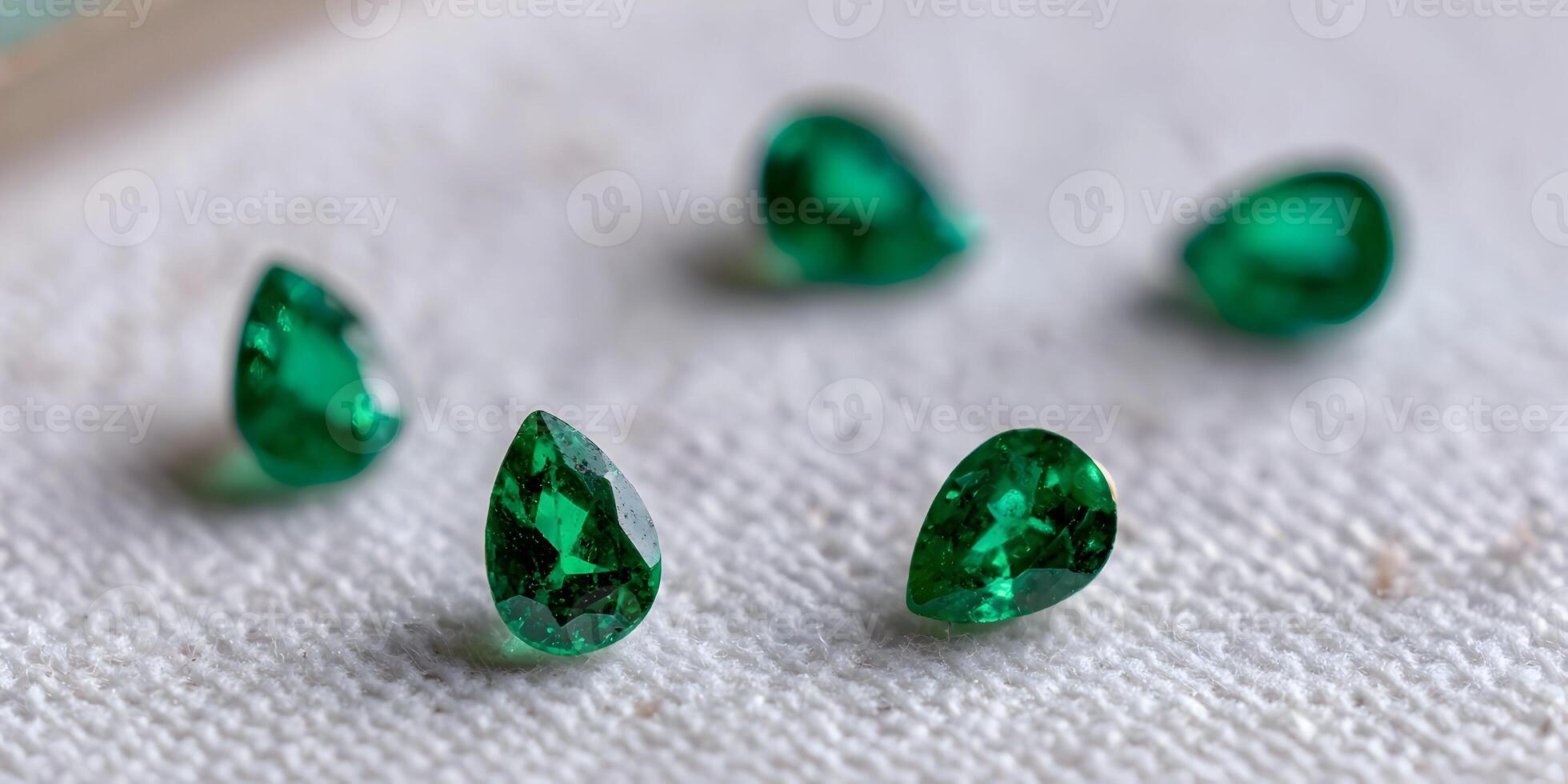 Five Pear Shaped Emerald Gemstones on White Fabric Close Up photo